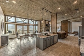 Een ruime keuken met grote ramen, een houten plafond en een centraal eiland.