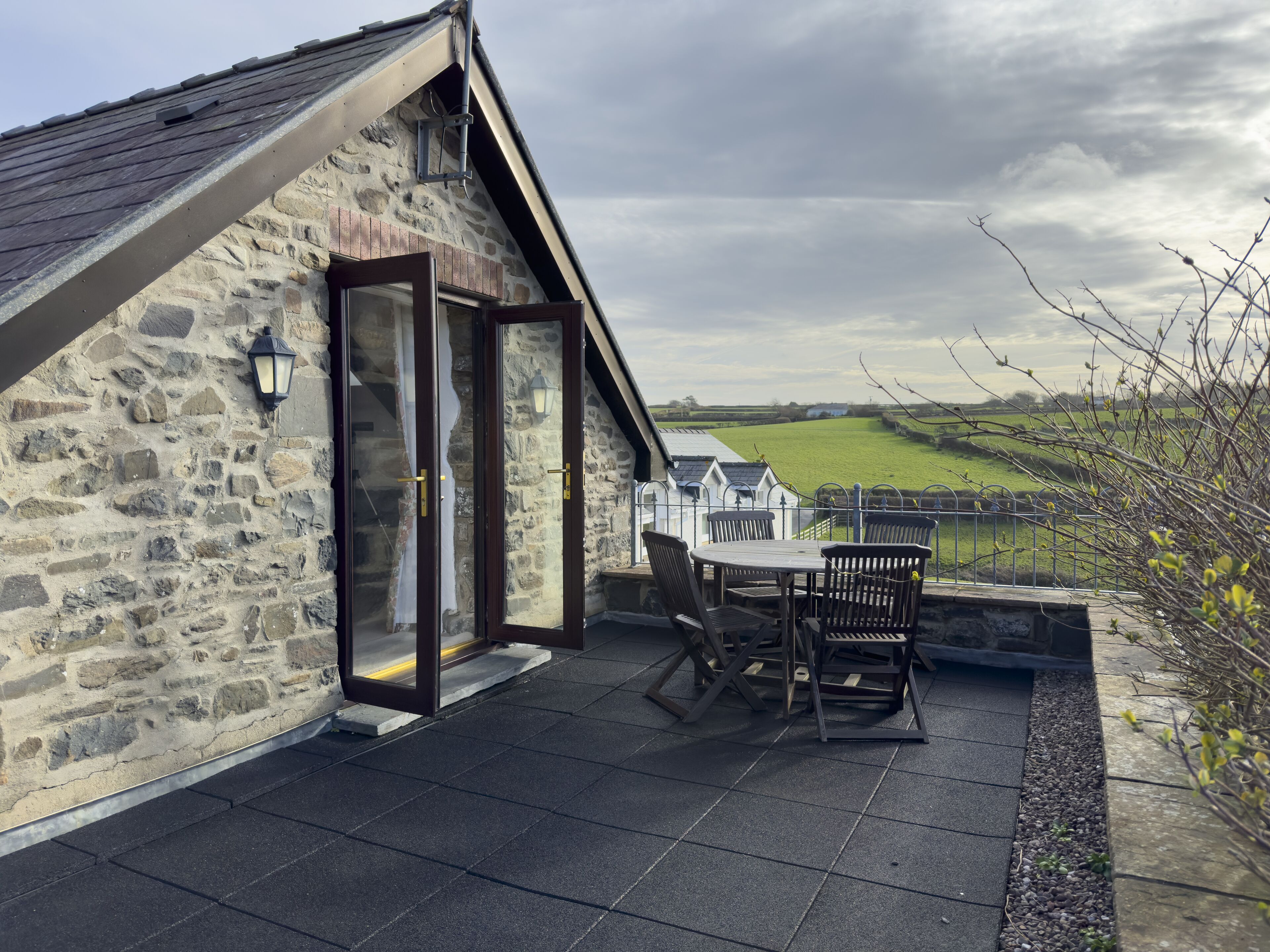 A stone building with a glass door and a patio with chairs and a table.