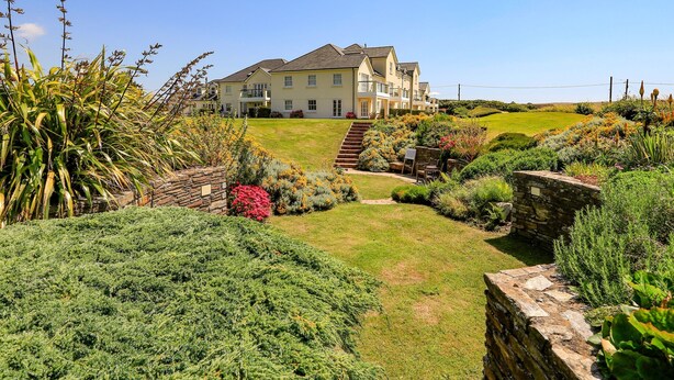 A large, two-story house with a well-maintained garden and a stone staircase leading to the entrance. - 5 Thurlestone Beach (Kingsbridge)