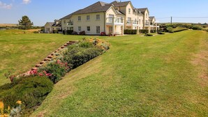 A large, two-story house with a well-maintained lawn and a flower bed in front. - 5 Thurlestone Beach (Kingsbridge)