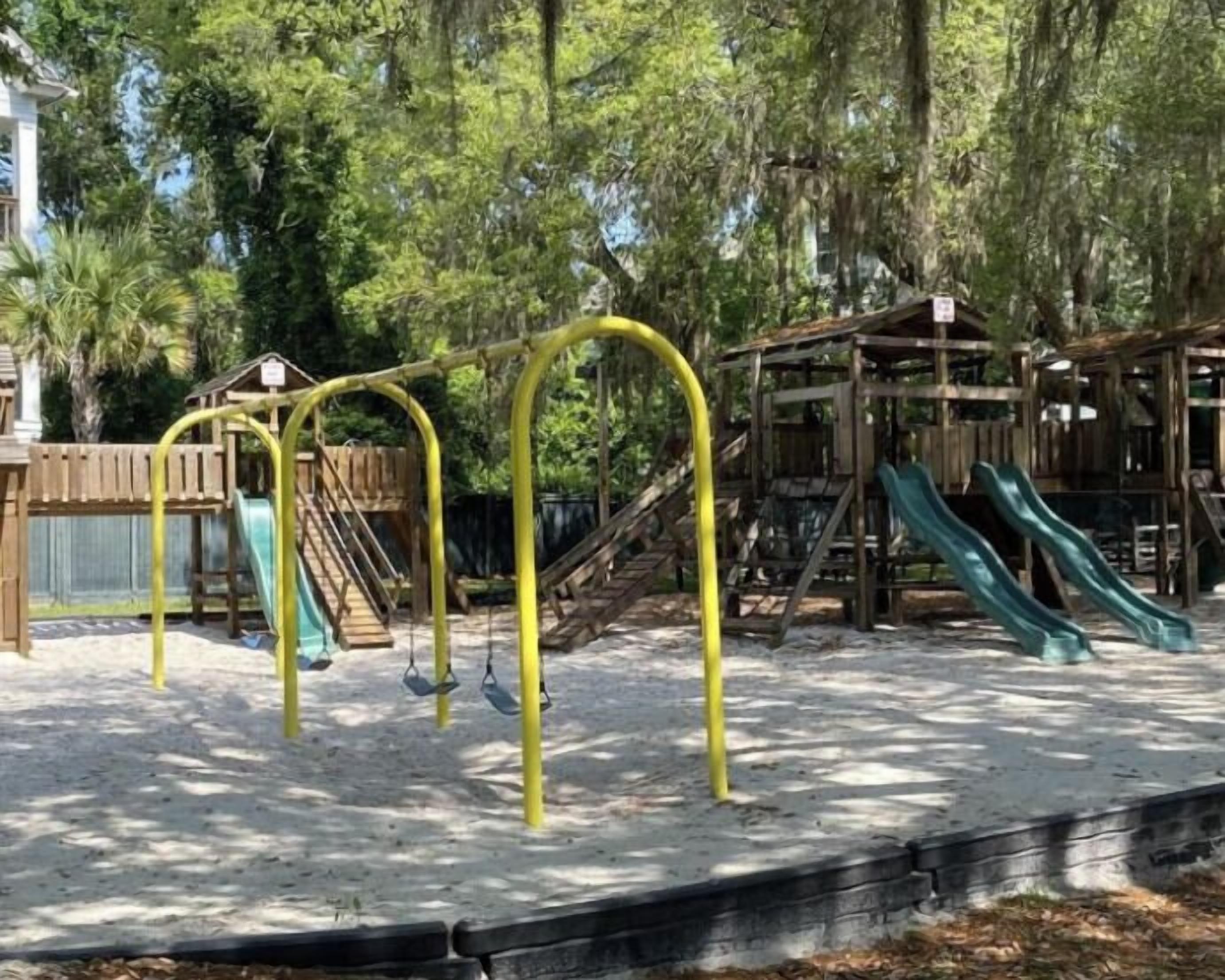 A playground with yellow swing sets and two slides.