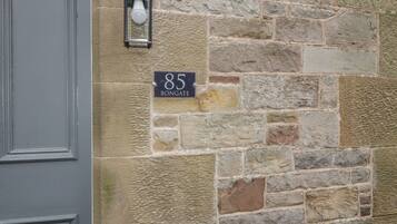 A stone wall with a house number sign and a lantern.