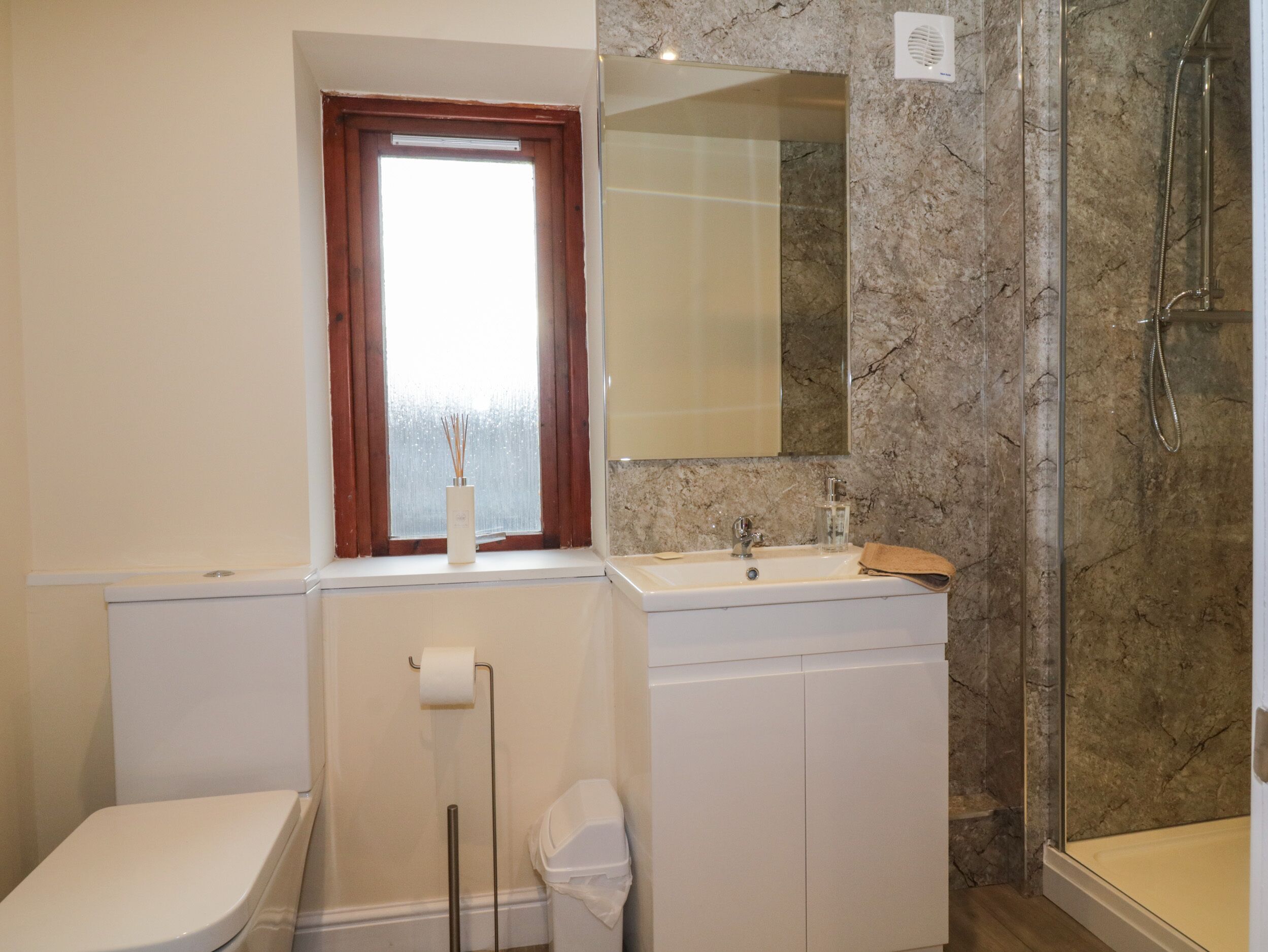Ein Badezimmer mit Toilette, Waschbecken, Spiegel und Dusche.