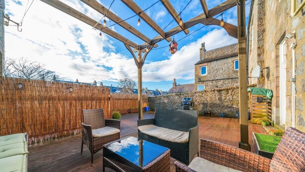 An outdoor patio with wicker furniture and a pergola. - Desswood Aberdeen City Apartment (Aberdeen)