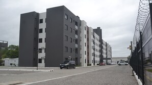 A modern multi-story building with a parking area in front. - Refúgio em Pelotas Com Nf-e, Ideal Para Famílias e Animais de Pequeno Porte (Tres Vendas Pelotas)