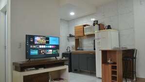 A modern kitchen with a built-in microwave, wooden cabinets, and a TV on a stand. - Refúgio em Pelotas Com Nf-e, Ideal Para Famílias e Animais de Pequeno Porte (Tres Vendas Pelotas)