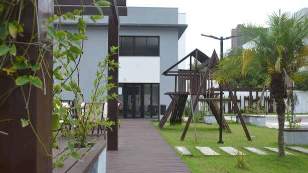 A wooden pathway leading to a modern building with a large window and a play structure. - Refúgio em Pelotas Com Nf-e, Ideal Para Famílias e Animais de Pequeno Porte (Tres Vendas Pelotas)