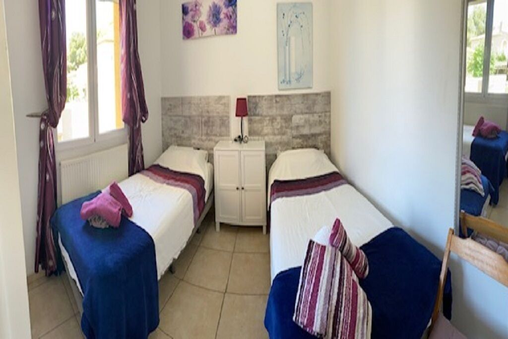 A room with two beds, a white cabinet, and a window with curtains.
