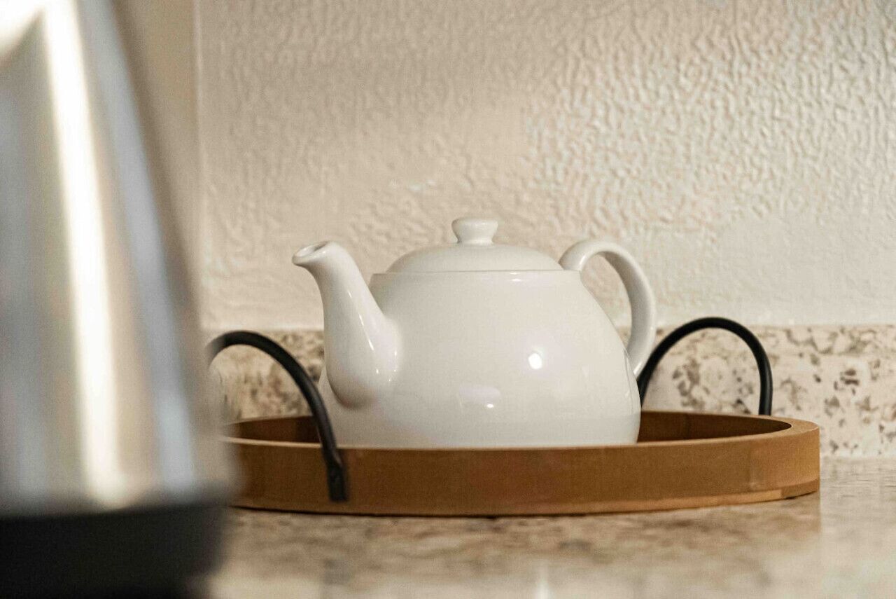 Een witte theepot op een houten dienblad.