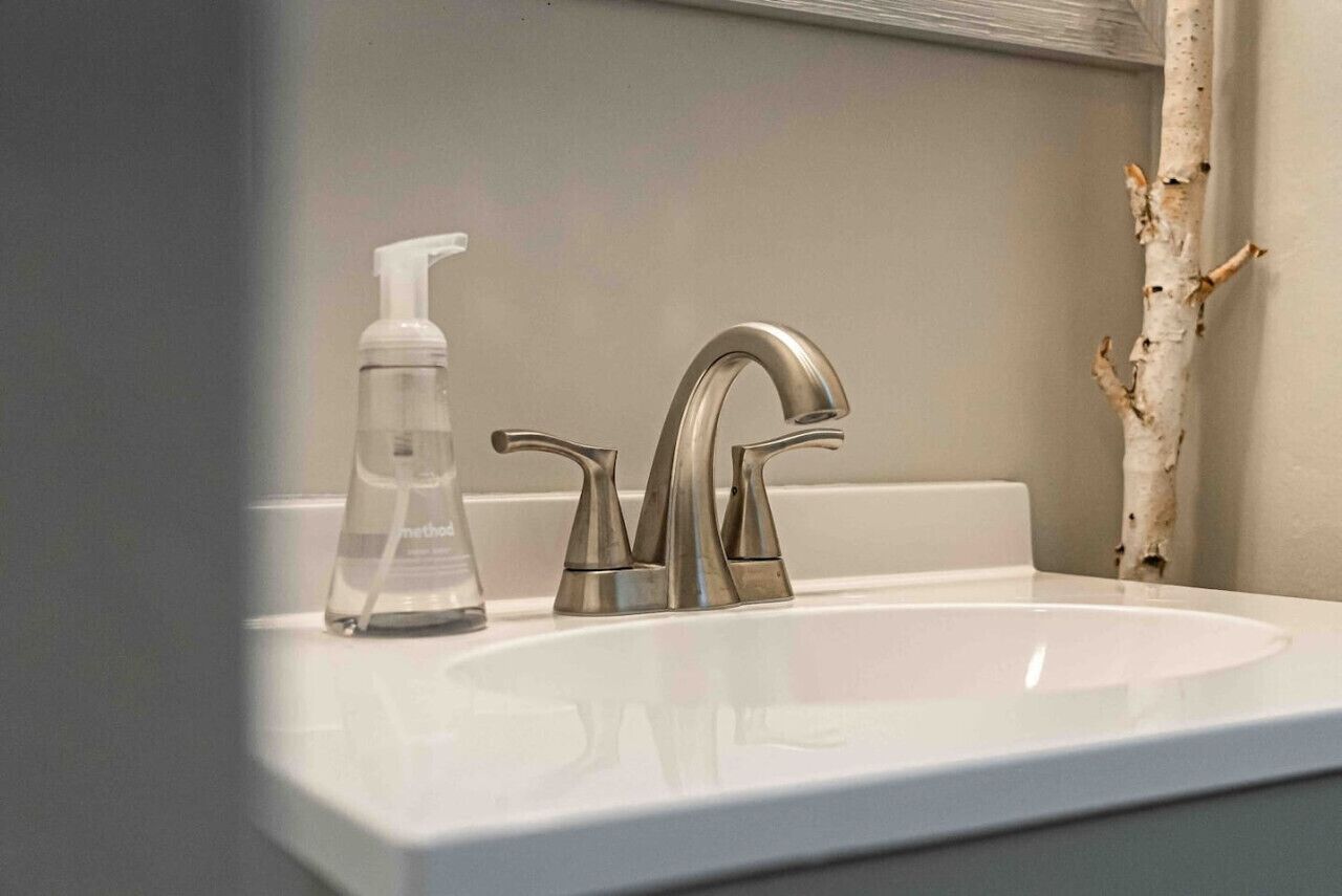 Un lavabo de salle de bain doté d’un robinet moderne et d’un distributeur de gel hydroalcoolique.