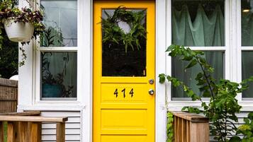 Una puerta amarilla con el número 414, un adorno de flores y plantas colgantes.