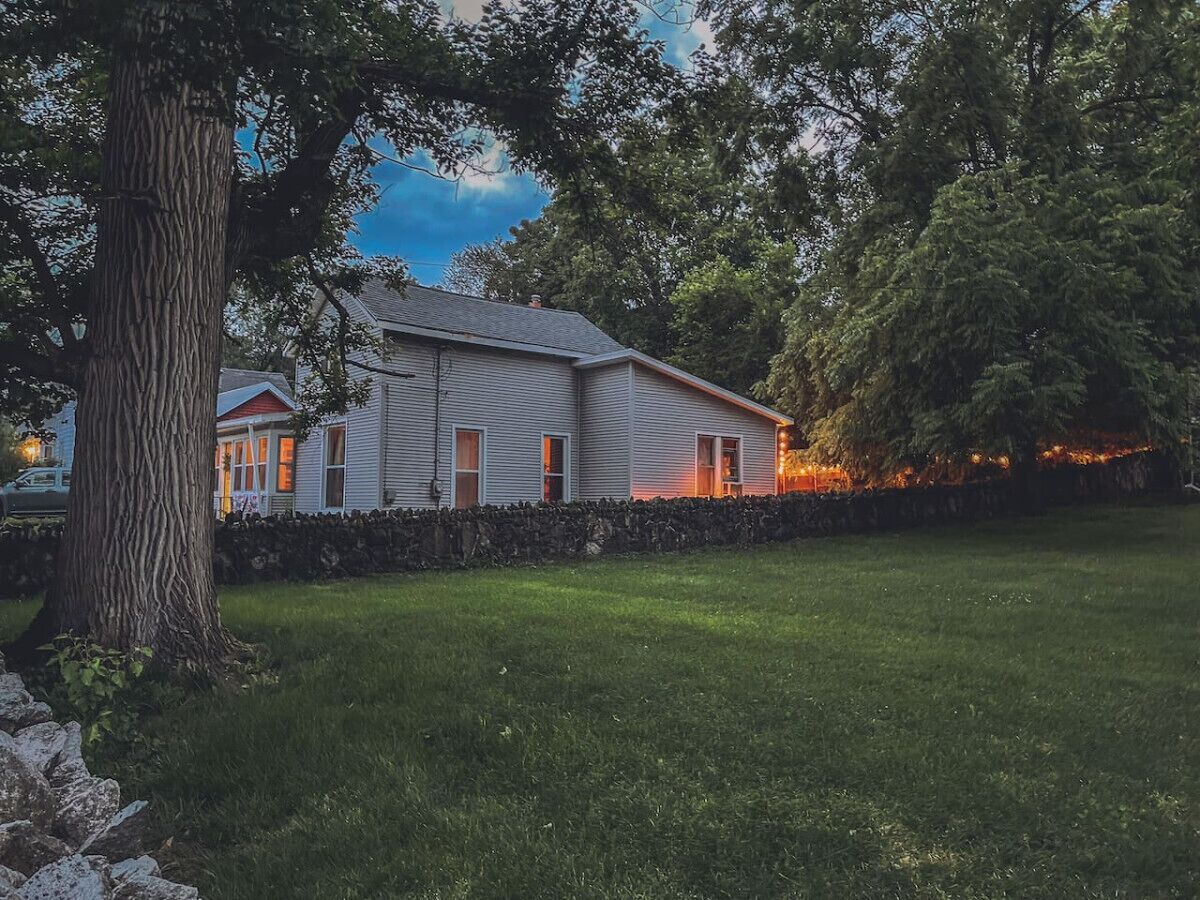 A two-story house with a stone wall and a well-maintained lawn.