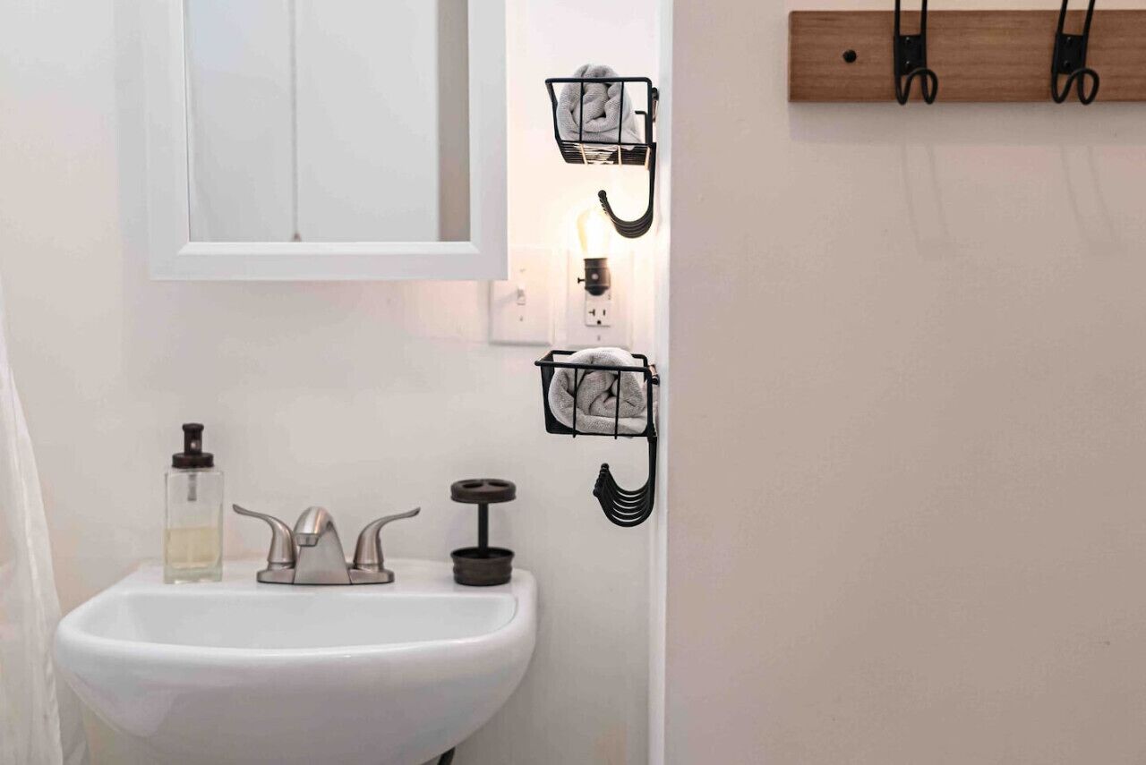 A bathroom with a white sink, a mirror, and two towel racks with towels.