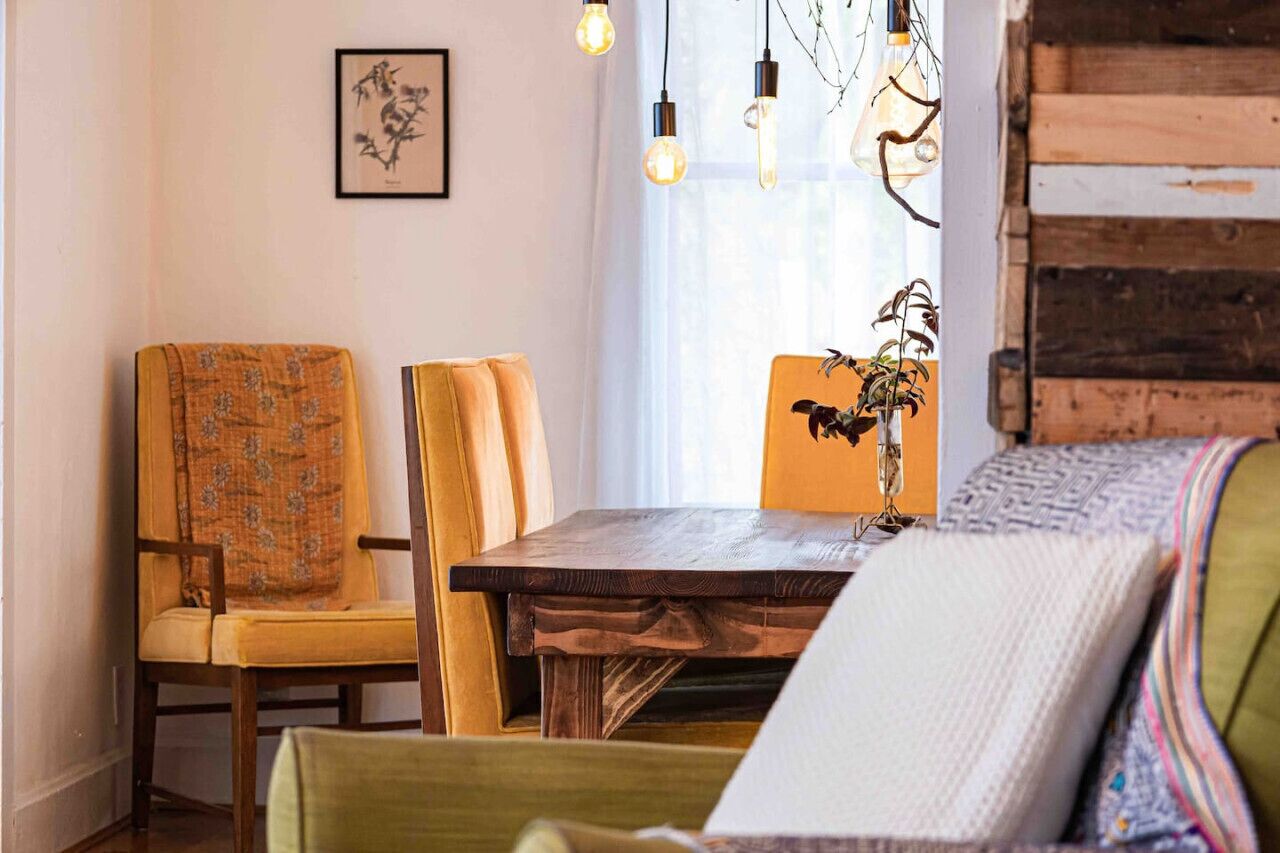 Un coin repas chaleureux avec une table en bois, deux chaises et des lampes suspendues.