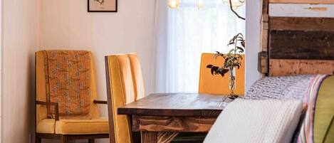 Un coin repas chaleureux avec une table en bois, deux chaises et des lampes suspendues.