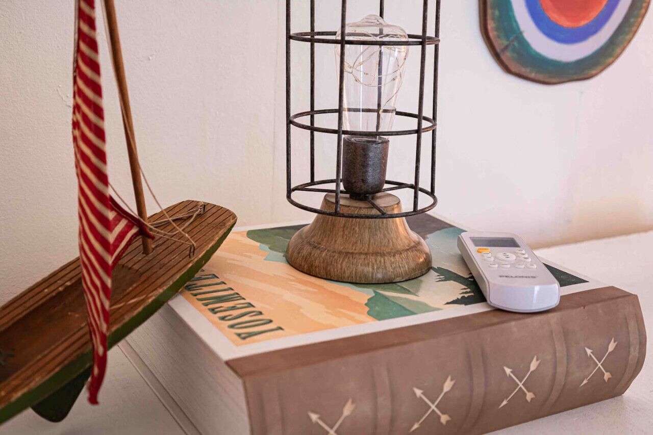 A wooden box with a remote control on top, a hanging chair with a striped cushion, and a decorative item with a glass enclosure.