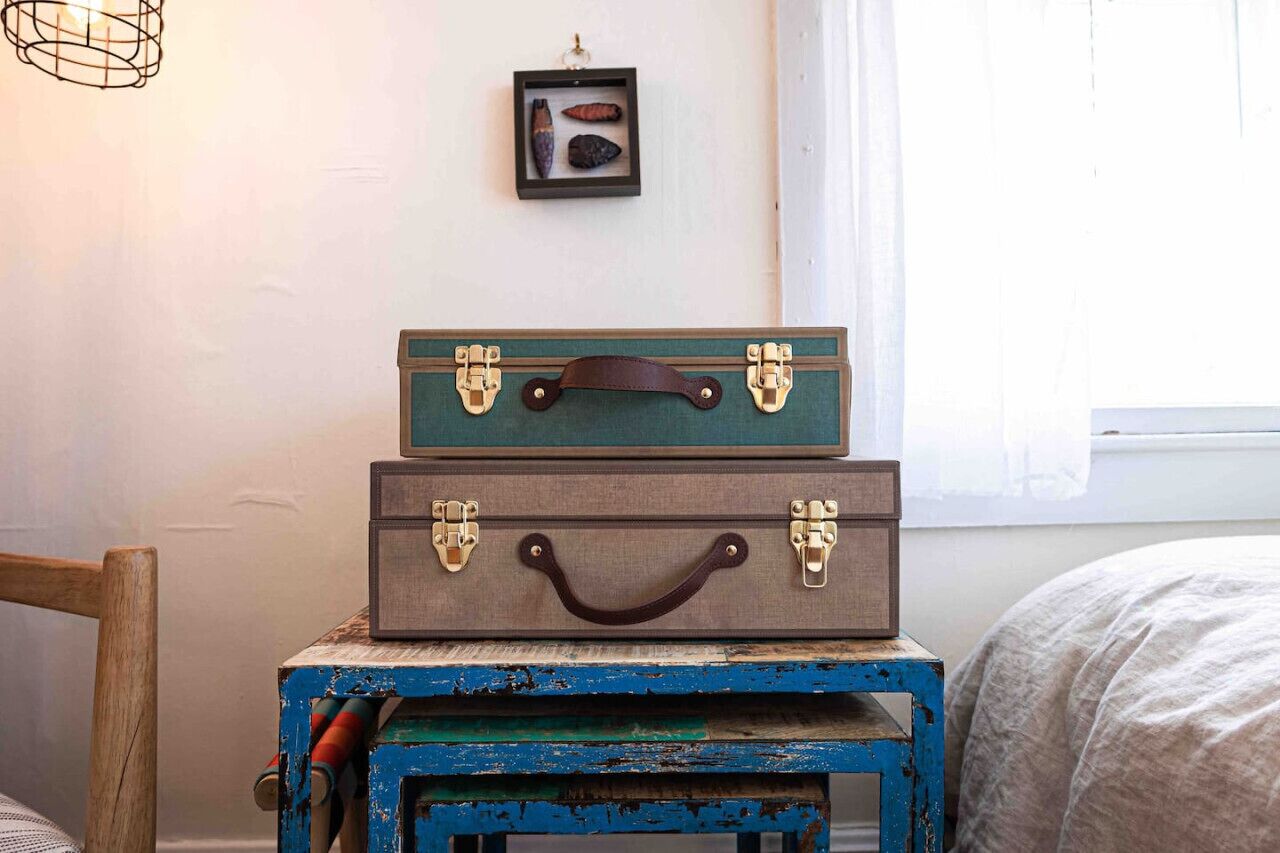 Two vintage suitcases stacked on a blue and green painted wooden table.