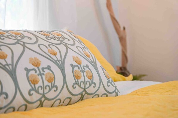 A bed with a patterned pillow and a yellow blanket.