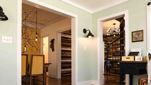 Un ampio corridoio con pavimento in legno, una scala e una sala da pranzo con sedie e tavolo.