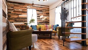 Un accogliente soggiorno con una parete in legno, un divano, un tavolino da caffè e una scala.