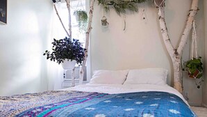 Una camera da letto con un letto, un'ampia finestra e una pianta fissata al muro.