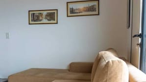 A living room with a beige sofa, two framed pictures on the wall, and a door to the right. - Cumbre (Ushuaia)