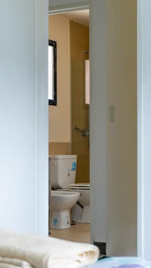 A narrow doorway leading into a bathroom with a toilet, a bidet, and a shower area. - Cumbre (Ushuaia)