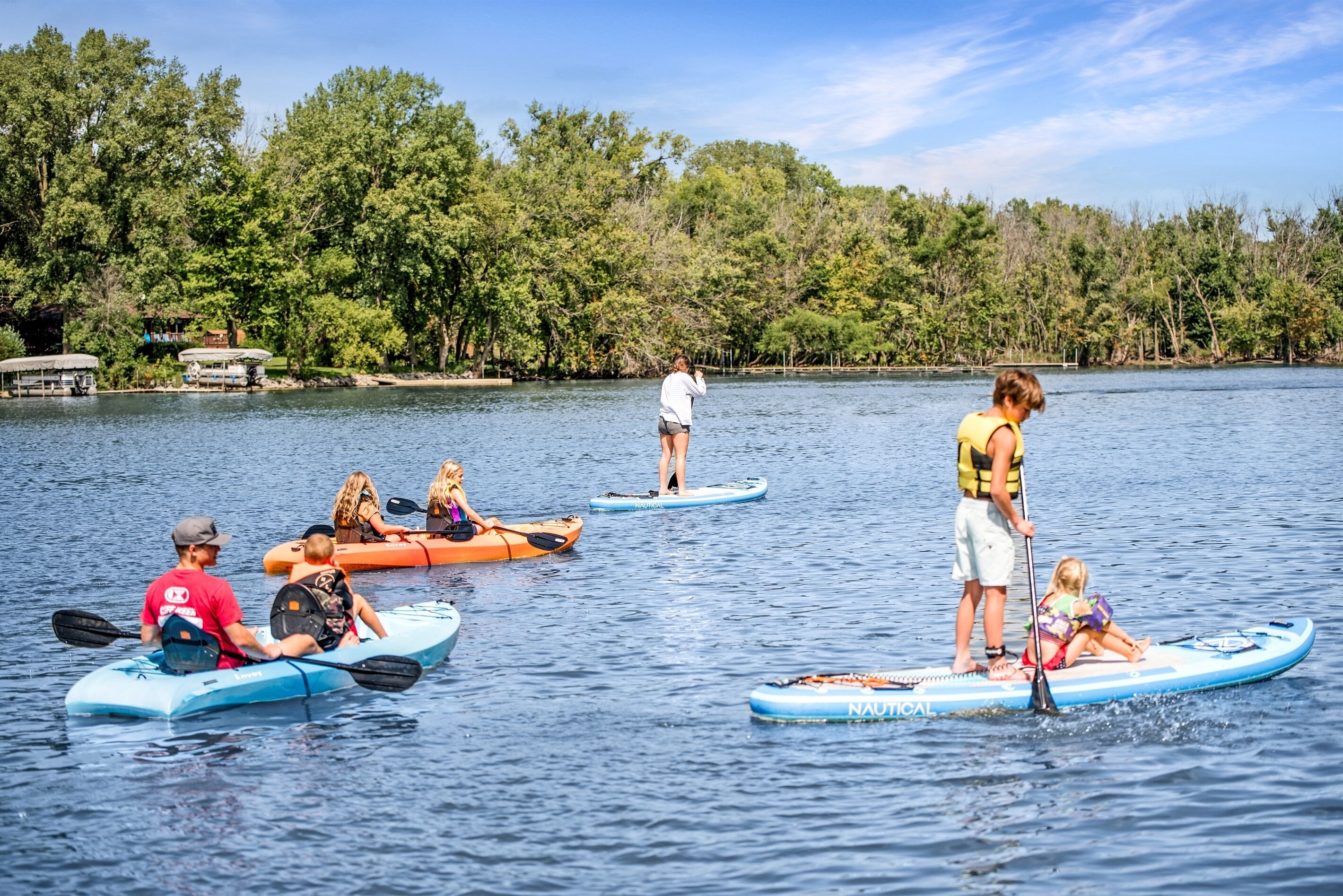 Personas haciendo paddleboard en un lago tranquilo rodeado de árboles.