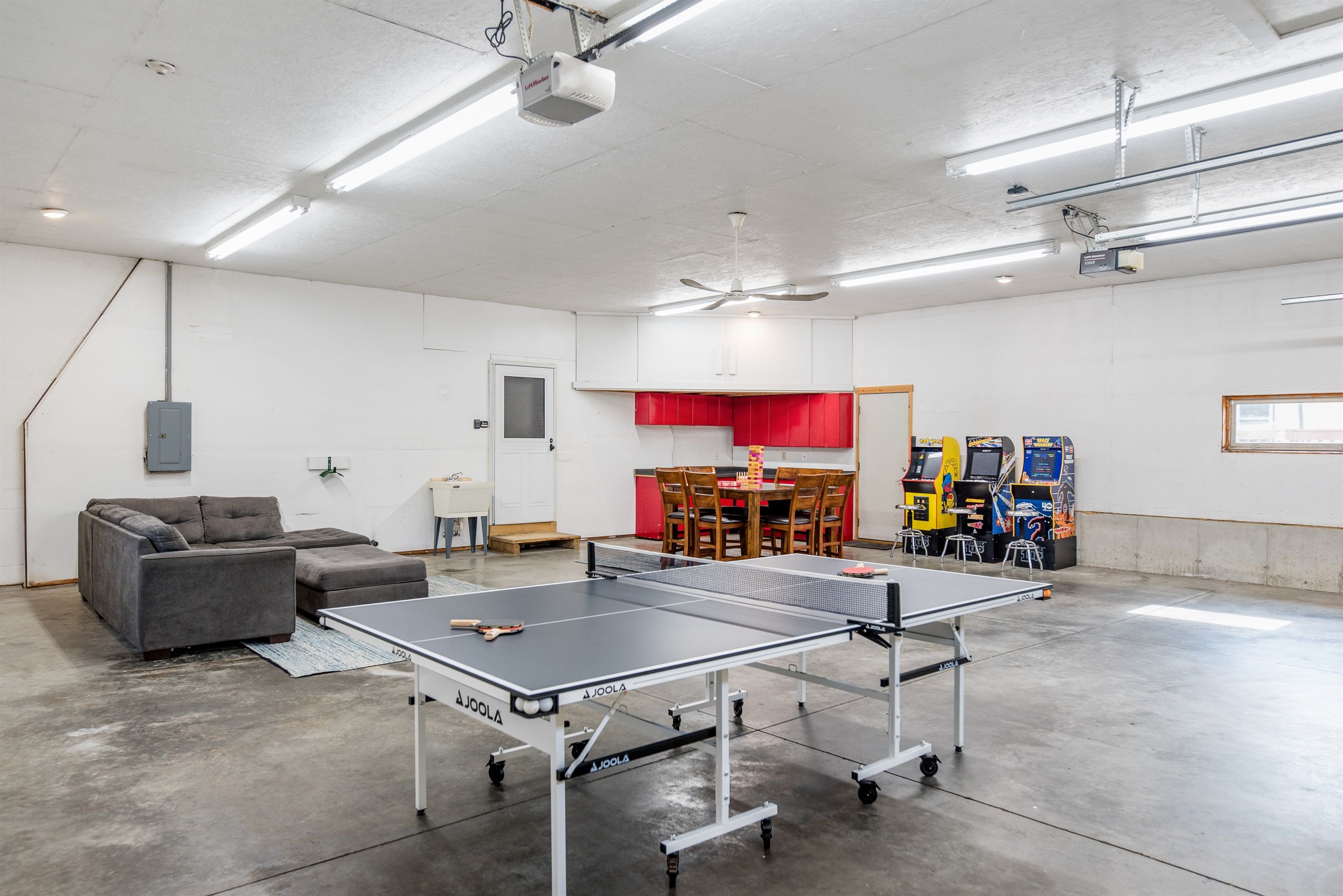 Une pièce spacieuse équipée d’une table de ping-pong, d’un canapé, d’une table à manger avec des chaises et de jeux d’arcade.