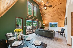 A dining area with a table set for four, a sofa, and a television mounted on the wall.