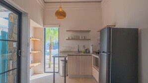 A modern kitchen with a black refrigerator, wooden cabinets, and a hanging pendant light. - Modern Villa 2 bedrooms- PetFriendly Beautiful Kitchen Pool close to beaches (Guanacaste Province)