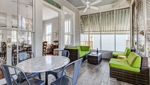 A spacious living area with a dining table, chairs, a green sofa, and a ceiling fan. - Historic Oasis. Heated pool, Historic Oasis. Heated pool spa large backyard (Galveston)