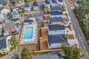 Vue aérienne d’un quartier résidentiel avec des maisons, une piscine et une route.