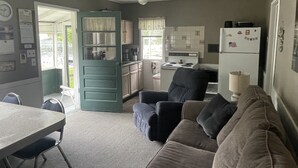 A compact living space with a kitchenette, a dining area, and a seating area with a sofa and armchair.