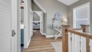 Ein Flur mit Holzboden, einer Treppe und einem Bett im Hintergrund.