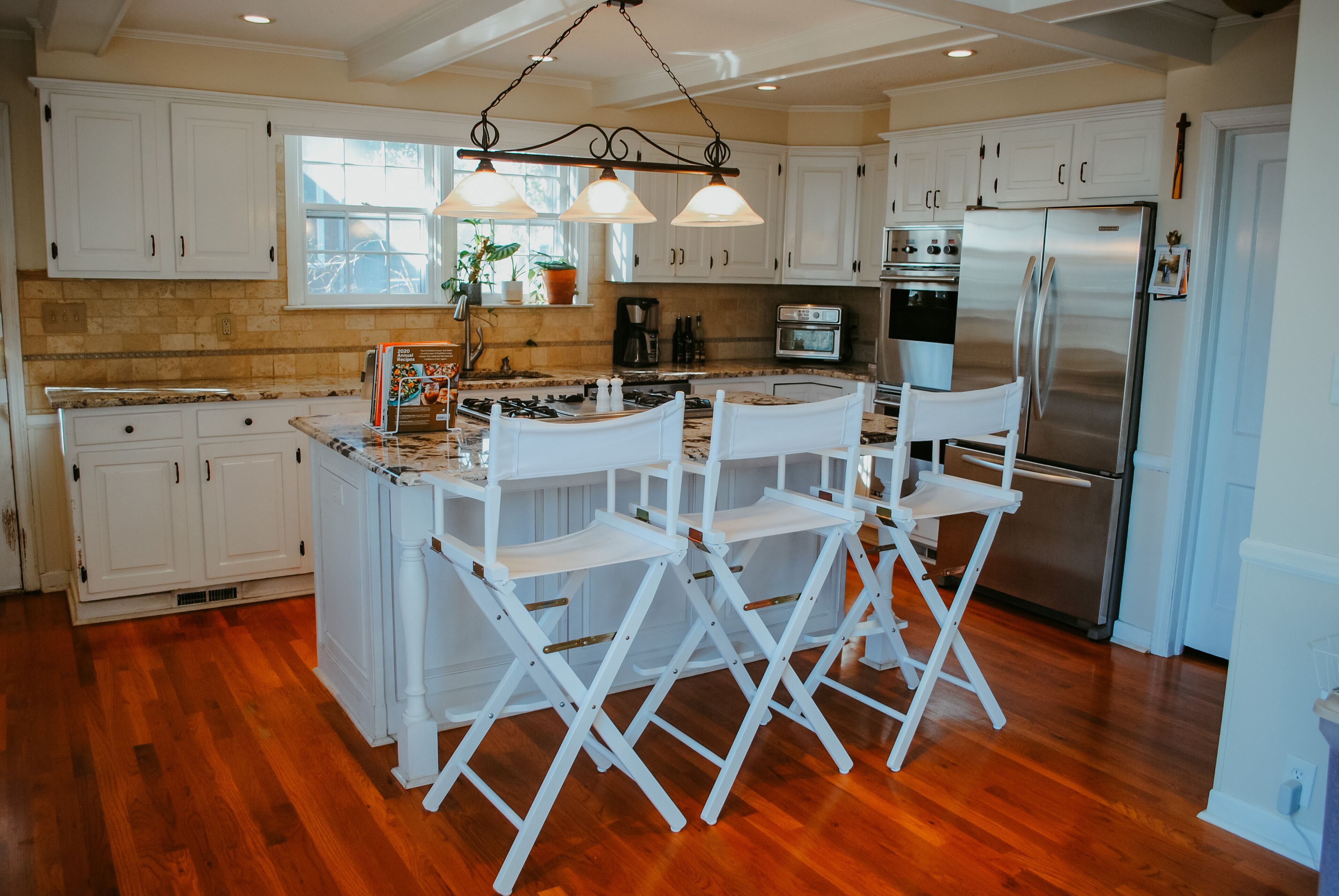 A kitchen with white cabinets, a stainless steel refrigerator, and a wooden island with bar stools.