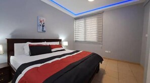 Relax in a stylish bedroom with a large bed, a nightstand, and a window with blinds.