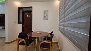 Cozy room with a round table and four chairs, a wooden door, and a framed picture on the wall.