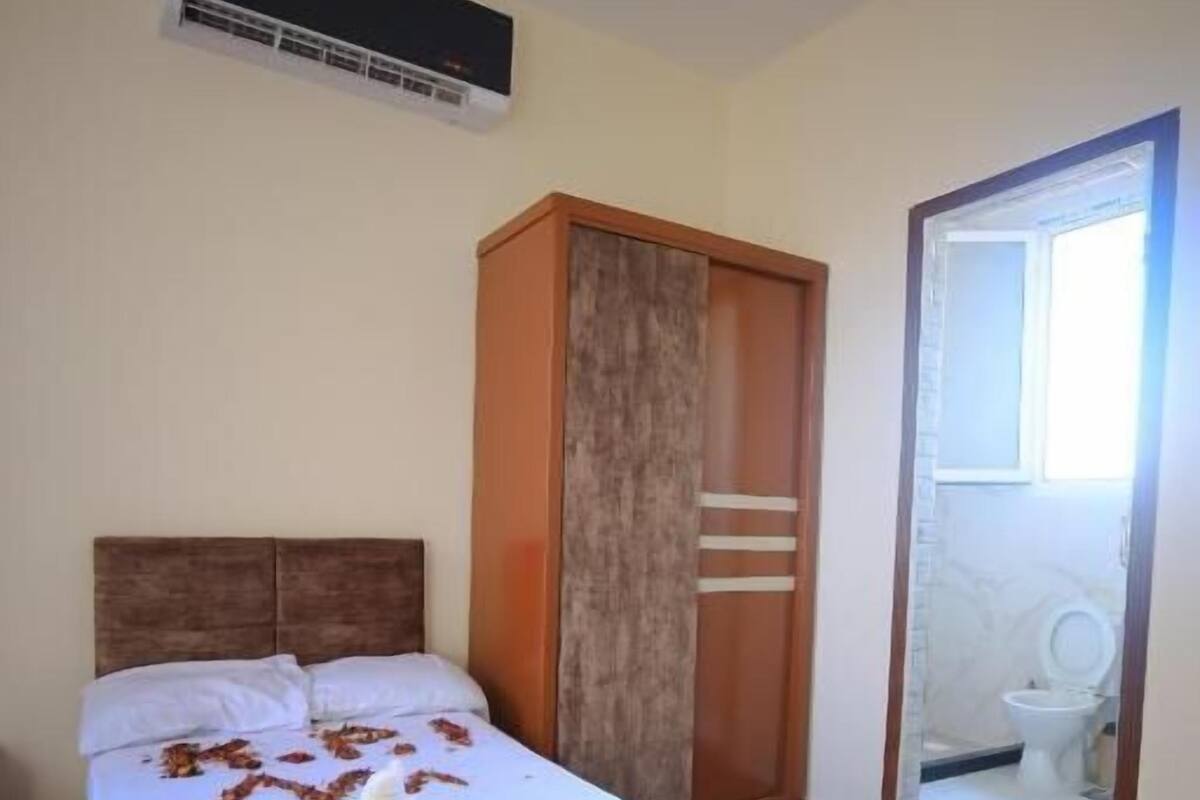 Ein Hotelzimmer mit Bett, Schrank und einem durchgegangenen Tür sichtbaren Badezimmer.