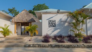A building with a thatched-roof structure, a sign with 'VR' and 'VA', and tropical plants. - Perfect Studio Kitchen Beautiful Pool Close to beach Avellanas AC PetFriendly (Guanacaste Province)