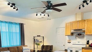 A living room with a brown sofa, a striped armchair, a coffee table, and a ceiling fan.