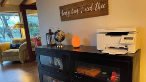 Un escritorio en casa con una impresora, un globo terráqueo y adornos sobre un mueble negro.