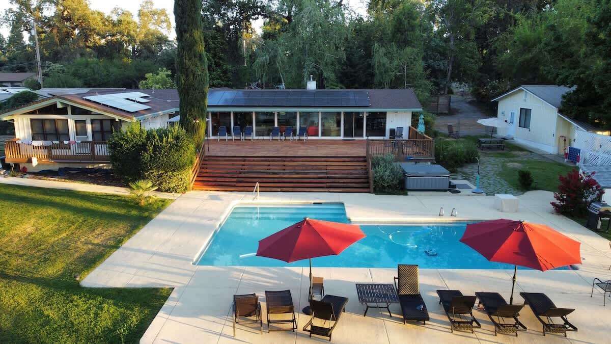 Un giardino con piscina, lettini prendisole e terrazza.