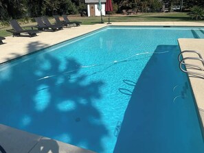 A rectangular swimming pool with clear blue water, surrounded by lounge chairs and a small building in the background. - River Estate-Luxury Pool,  Spa (Anderson)
