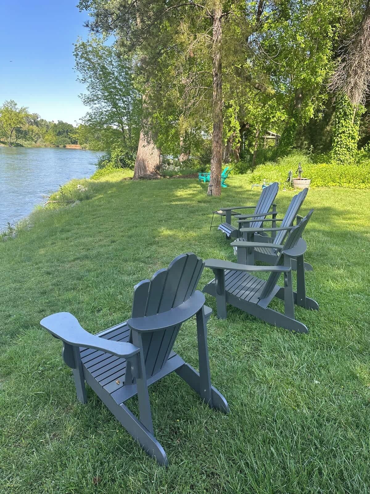 A lakeside outdoor seating area with Adirondack chairs and a table.