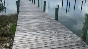 A wooden pier extending into calm water with boats docked nearby.