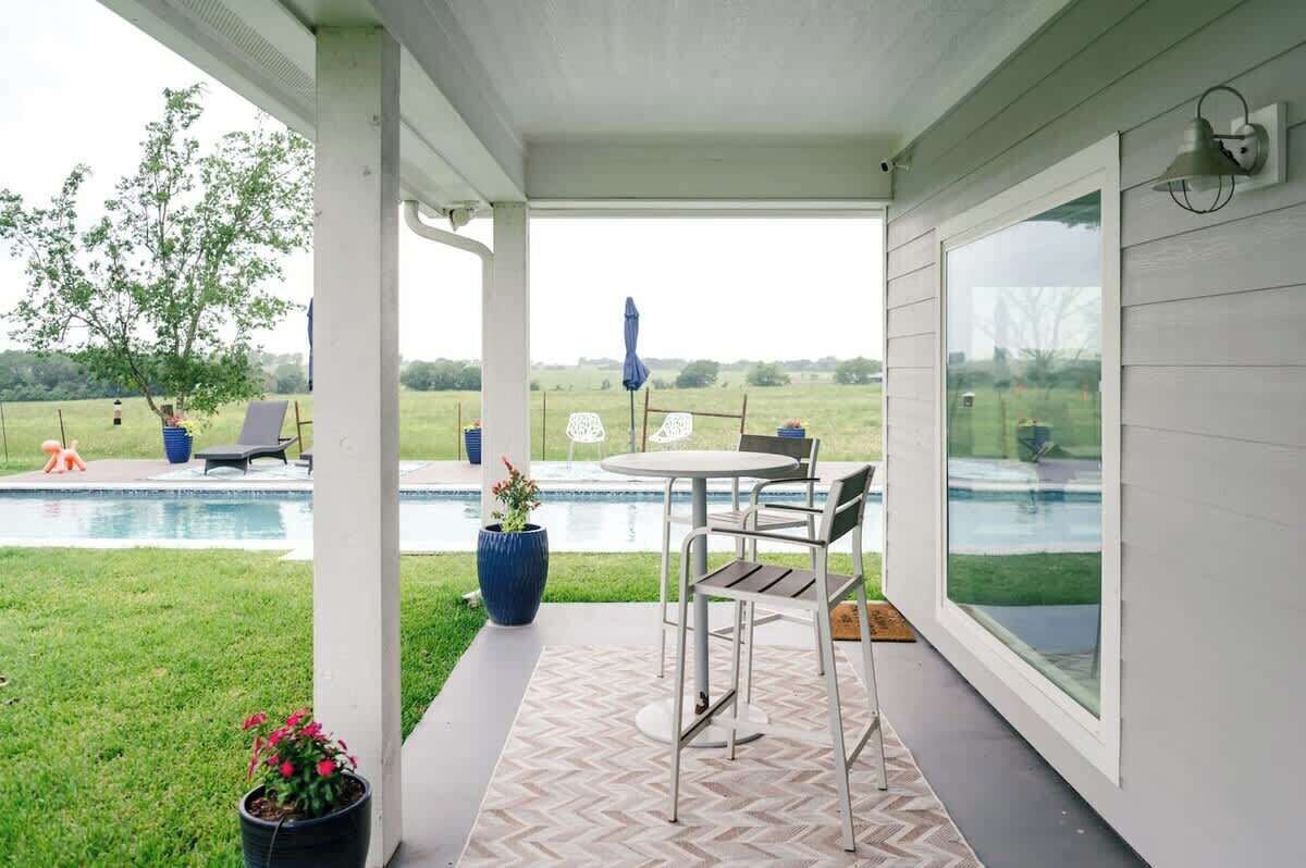 Un patio cubierto con piscina, mobiliario exterior y vistas del paisaje circundante.