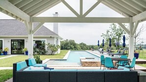 A covered outdoor area with a pool, seating, and umbrellas.