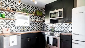 A kitchen with black cabinets, a stainless steel oven, a microwave, and a white refrigerator. - Walkable to Fayetteville + Wine Bar | Sleeps 3 (Fayetteville)