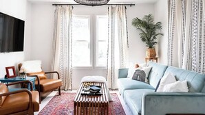 A living room with a light blue sofa, a brown leather armchair, a wooden coffee table, and a patterned rug. - Walkable to Fayetteville + Wine Bar | Sleeps 3 (Fayetteville)